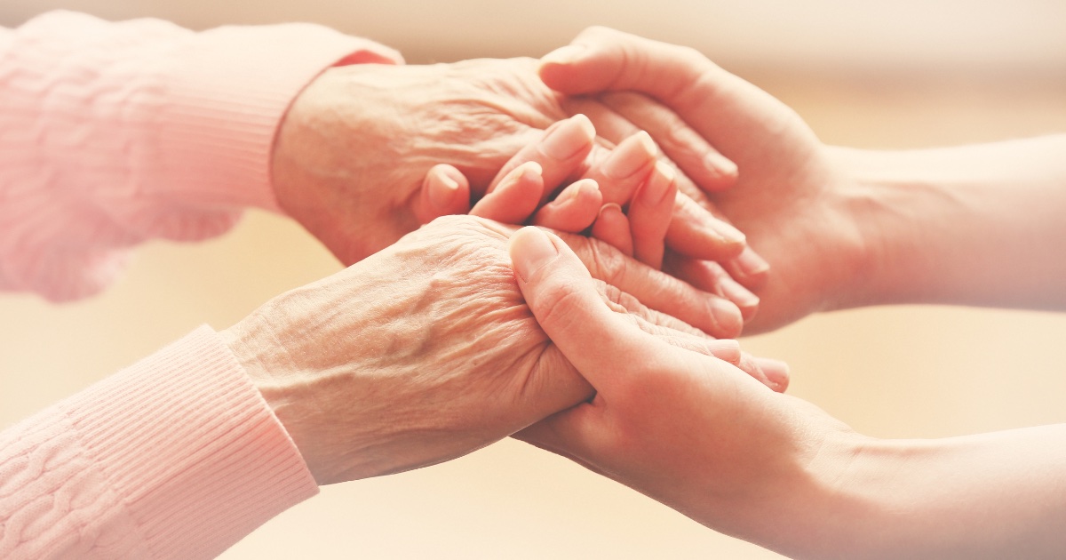 A set of young hands holds a set of older hands, showing the tender care needed a professional caregiver.