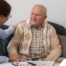 A caregiver compassionately listens to an older man, representing the kind of patience and empathy that help with communicating with clients who have dementia.