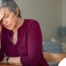 A woman holds her head in her hand, representing the stress that new family caregivers go through.